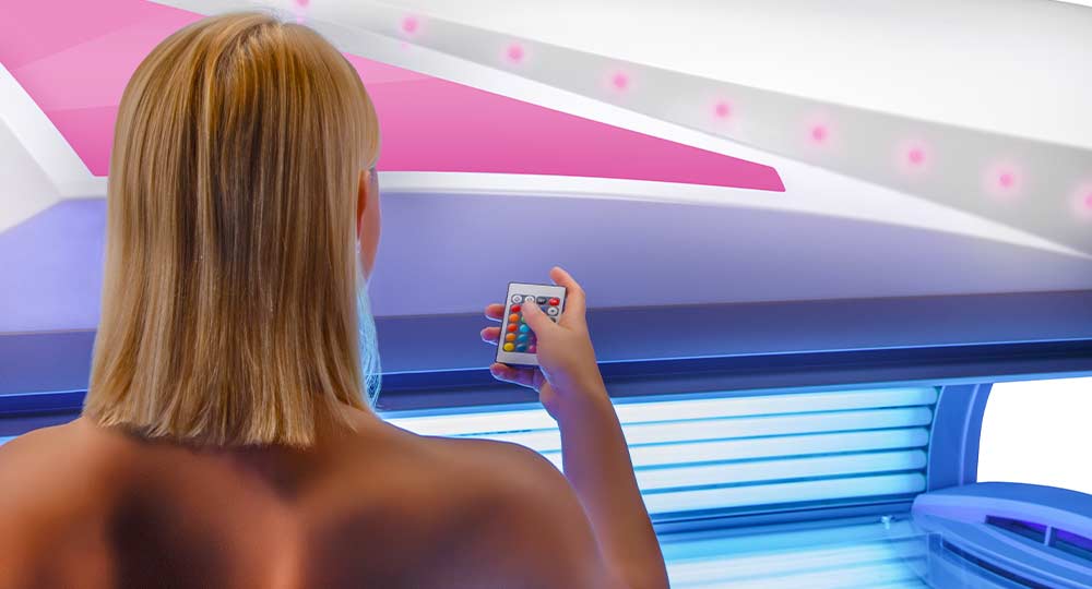 Ultrasun Q22 sunbed in Dream White Metallic with a woman standing in front holding a clicker