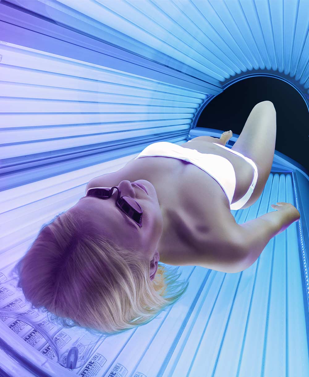 Woman laying inside of a sunbed with purple and blue lights