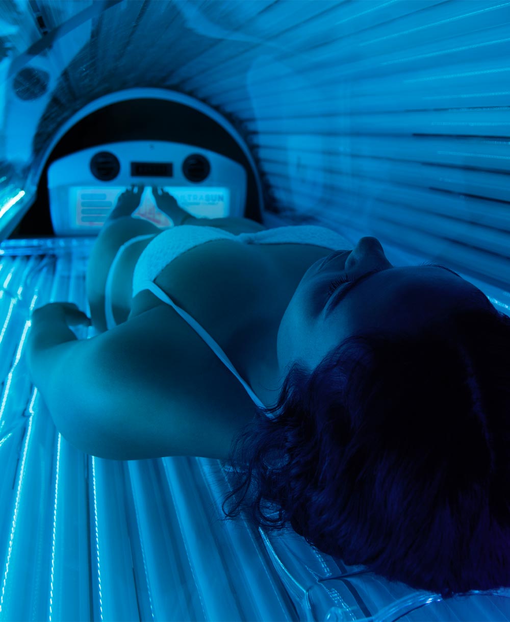 Woman laying inside a sunbed with blue lights