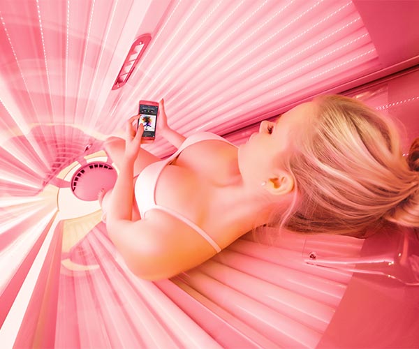 Woman tanning inside a pink sunbed
